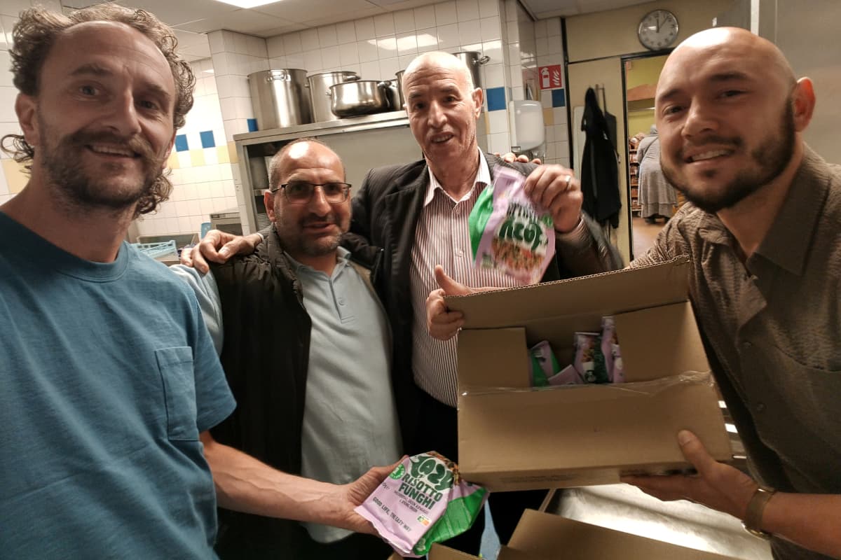 Buurthuismedewerkers ontvangen een doos met maaltijden en tonen trots de verpakkingen